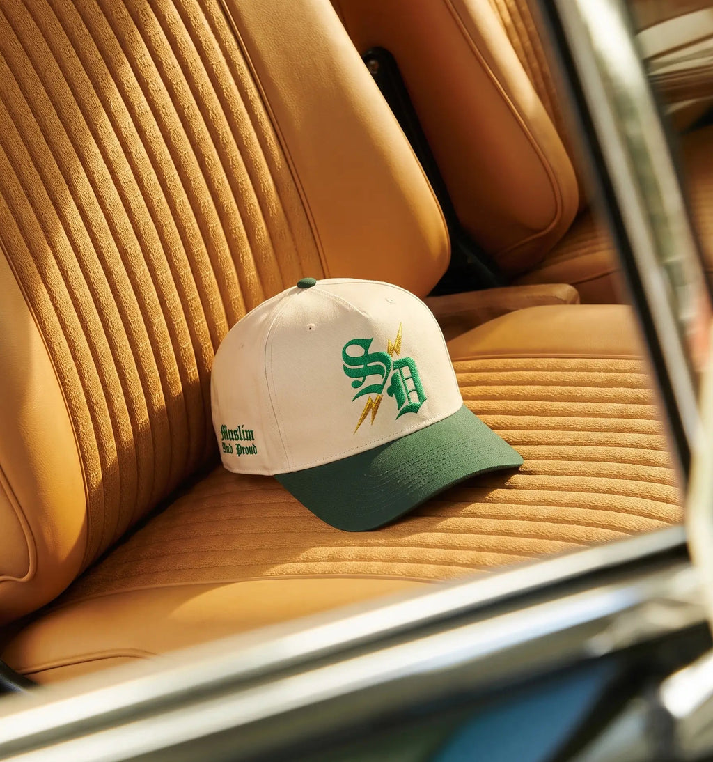 Street Dawah Apparel structured 5-panel cap in cream and green with Proud Muslim embroidery on a vintage car seat